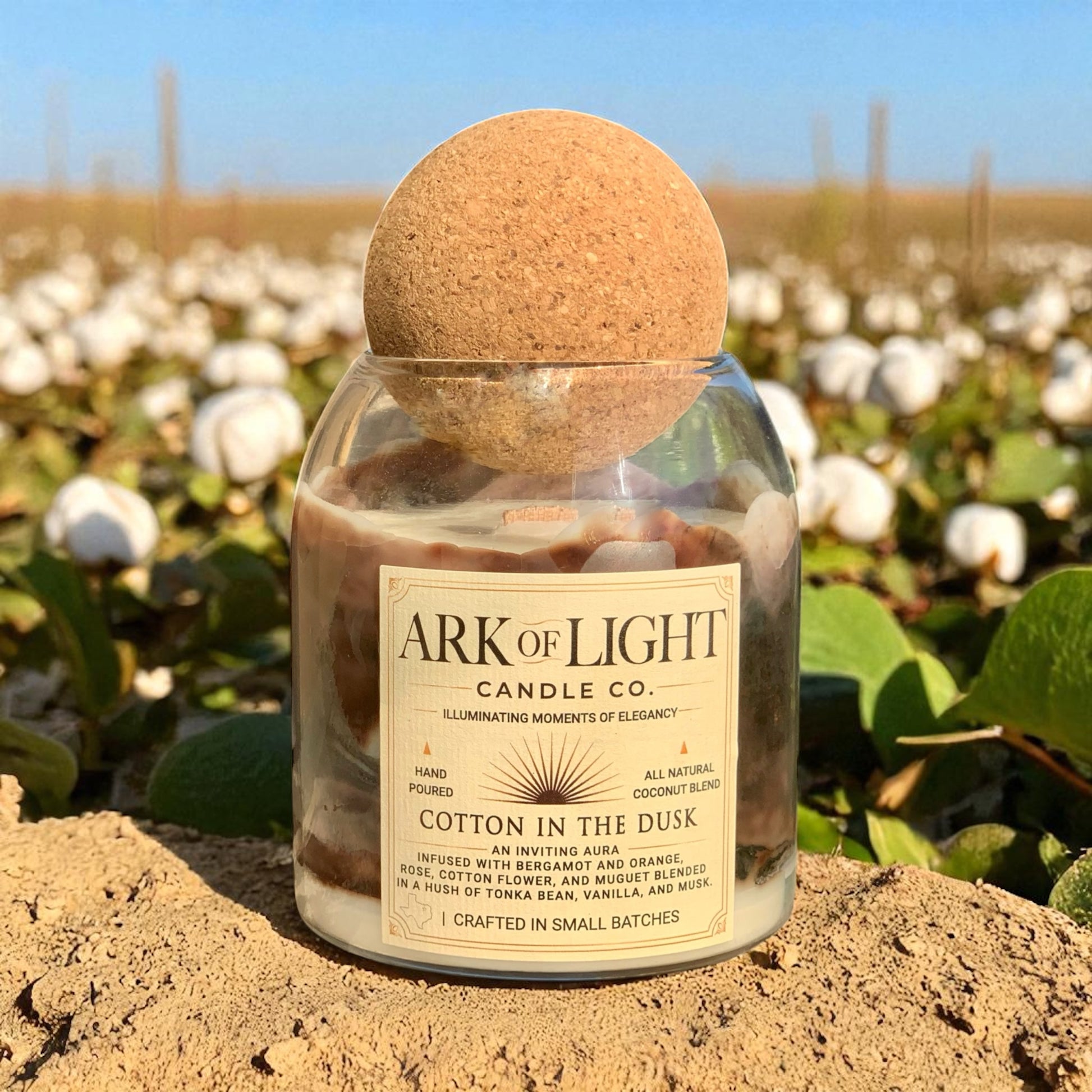 Candle with cork lid in a field of cotton, featuring 'ARK OF LIGHT CANDLE CO.'